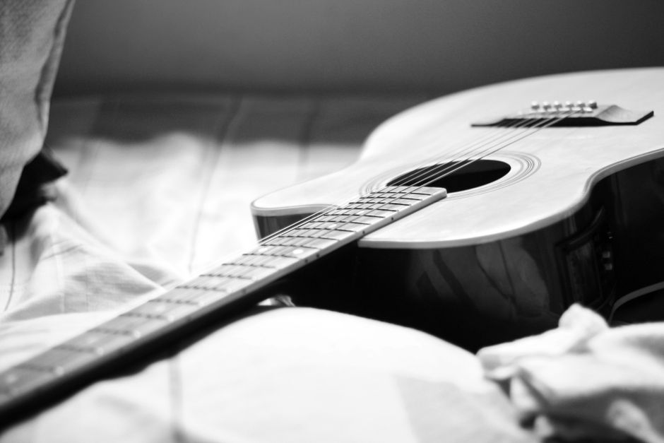 Akustická gitara opretá o drevenú stoličku